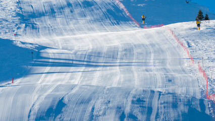 Detailed view of a groomed ski slope with safety fencing and snowmaking equipment, highlighting modern winter resort preparation and alpine skiing infrastructure