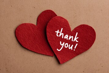 Two red hearts on brown background expressing gratitude with a handwritten 'thank you!' message.