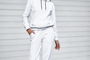Female model posing in white joggers and sweatshirt outside