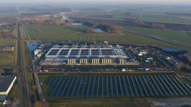 Aerial view of the extensive Google data center gleaming under the sun, surrounded by verdant fields and serene canals, a modern oasis in the Dutch landscape, Winschoten, Groningen, Netherlands.