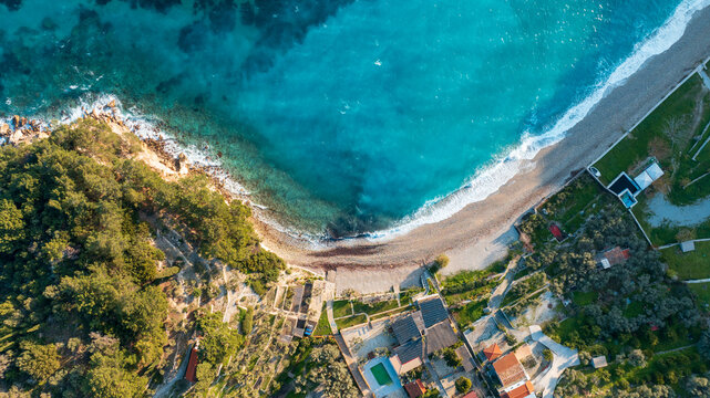 Top down aerial view of a sand beach and houses next to the calm sea on Samos island, Greece