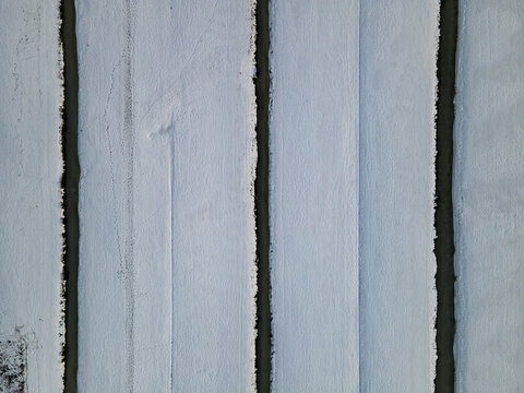 Aerial view of stark white lines contrast sharply against the dark, narrow channels, creating a minimalist, abstract pattern from above, Delft, South Holland, Netherlands.