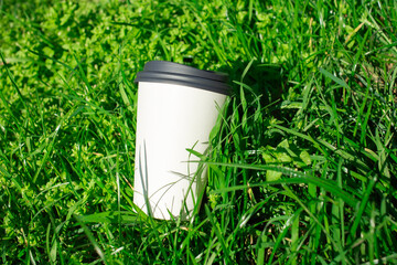 Discarded paper cup lying on green grass as  pollution concept