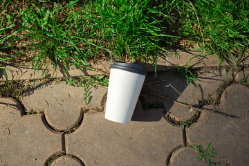 Discarded paper cup on curb as urban pollution concept
