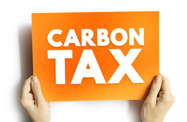 CARBON TAX text on card held by hands, concept of environmental policy, emissions, and climate change economics
