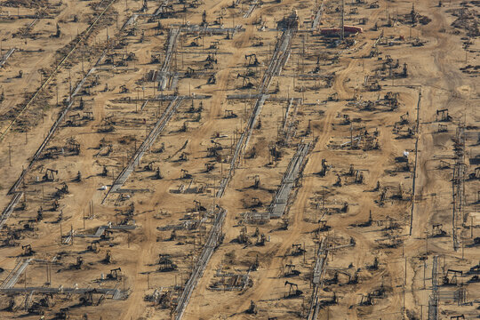 Aerial view of a vast oil field dotted with pump jacks under the harsh desert sun, Bakersfield, California, United States.