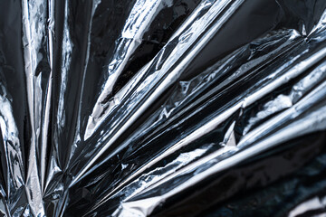 Abstract metallic foil texture with sharp diagonal folds and reflections