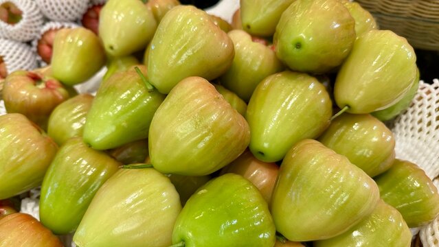 Pile of fresh green wax apples or rose apples at a tropical fruit market.