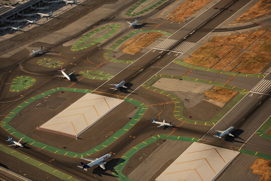 San Francisco, United States - 27 June 2025: Aerial view of the sprawling airport runways, where silver planes rest against the stark concrete under a clear sky.