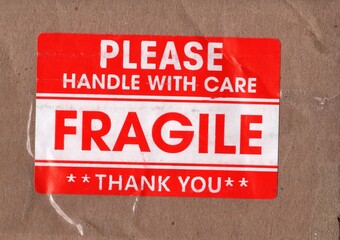 A red FRAGILE sticker on brown packing board.