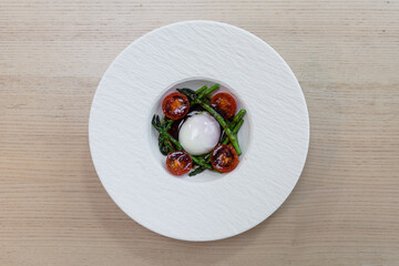 A plate of asparagus and tomato with poached egg.