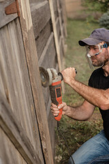 Man work on holiday repairing and renovating a country house - summer chores in the backyard and garden - power tool work