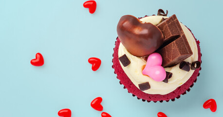 Red velvet cupcake decorated with heart chocolate and pink heart on blue background, valentines day, celebrating love concept