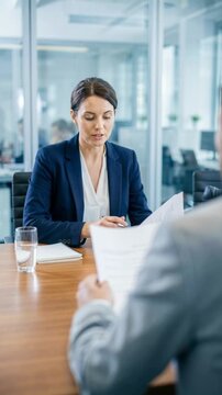 Vertical video of a female HR manager interviewing a male candidate. Professional recruitment and hiring process in a modern office. Job interview and career concept