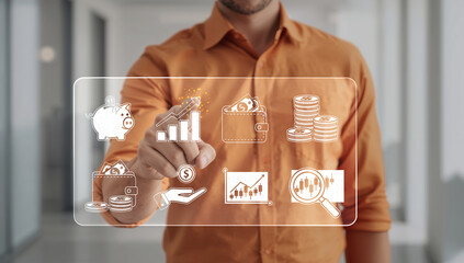 Man in orange shirt interacting with a futuristic holographic financial interface displaying various business and investment icons.