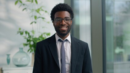 African American man business guy male businessman near window think looking at camera smiling happy portrait job ambition professional worker indoors smile work success ethnic entrepreneur headshot