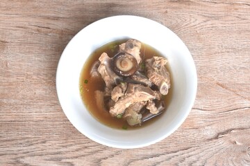 boiled pork bone topping black mushroom in clear Chinese herb soup on bowl 