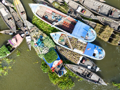 Aerial view of boats laden with produce and coconuts afloat on the waterway, a vibrant scene of trade and transport, Pirojpur, Barisal Division, Bangladesh.