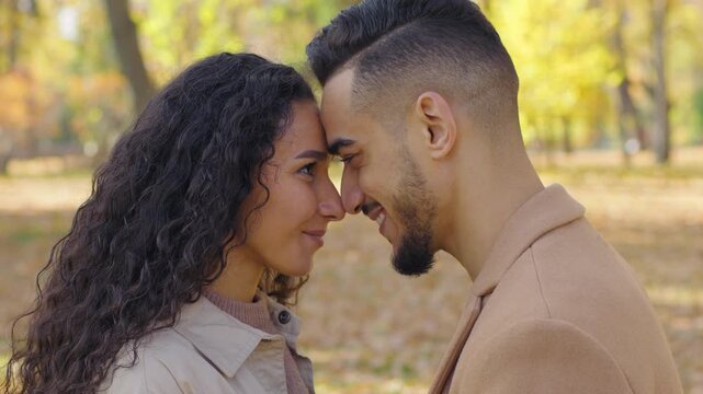 Loving married Hispanic couple touching foreheads noses kissing in autumn park city happy smiling laughing married man woman heads touched outdoors romantic date family tender love affectionate bond