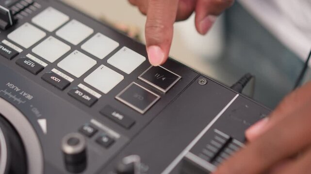 Closeup black DJ hands tapping pads on compact controller, cueing tracks, adjusting fader and knob, warm indoor lighting, focused rhythm creation, urban street vibe, visible jog wheel and cable,