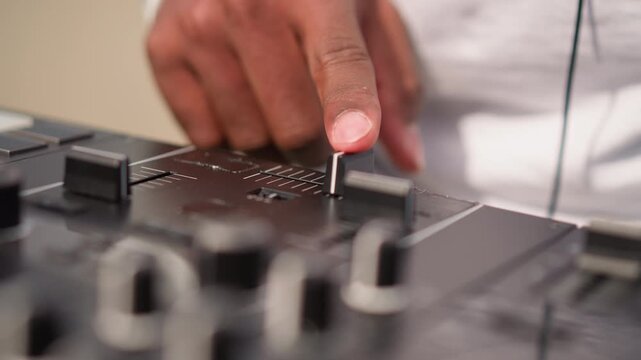 closeup black DJ adjusting mixer knob, studio producer finetuning levels and EQ, focused engineer workflow, headphones on monitors, sample editing and arrangement, calm creative atmosphere, remix