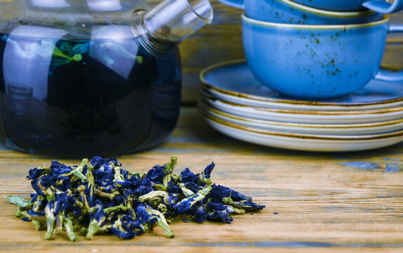 Refreshing blue  tea in cup and teapot on grey wooden table against gray background