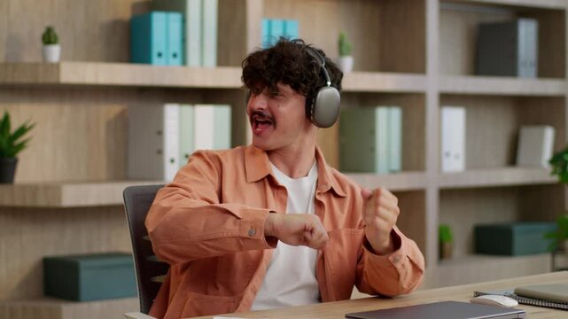 Successful active Caucasian business man finishing job close laptop dancing listening music in headphones end work day businessman accomplish working computer dance listen song in earphones at office