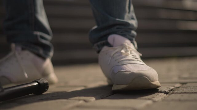 closeup light sneaker on pavement near microphone stand busker foot taps rhythm against cobblestone under warm sunset light, jeans cuff visible, urban stair background, intimate motion and groove