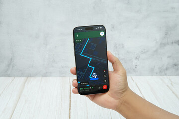 Hand holding smartphone displaying generic navigation map interface for route guidance and location tracking.