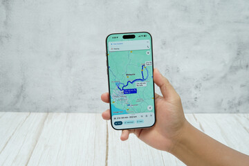 Hand holding smartphone displaying generic navigation map interface for route guidance and location tracking.