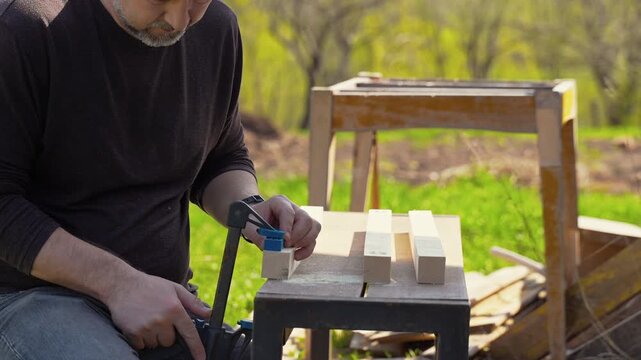 Man preparing woodworking jig and wooden boards on outdoor workbench, DIY carpentry process, home improvement, manual work with tools, craftsmanship and construction concept