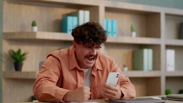Irritated annoyed European business man lose with mobile phone loser businessman Caucasian distress male guy suffering with smartphone failure bet fail lost money debt feeling anger furious in office
