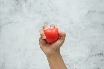 Hand holding a red heart symbol representing love, care, and emotional connection.