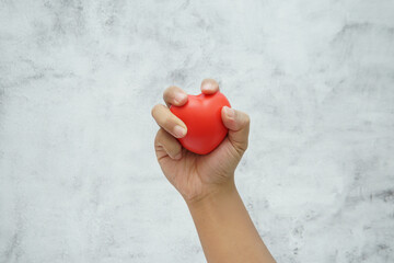 Hand holding a red heart symbol representing love, care, and emotional connection.