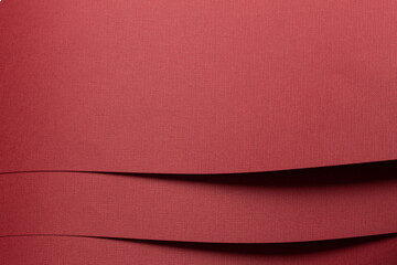 Red layered paper background with multiple folds. Matte textured surface and rich warm color.