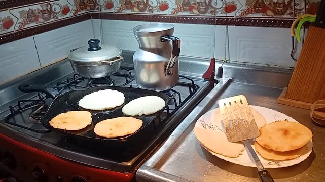 Preparing a healthy breakfast with corn arepas cooked on a griddle in a beautiful kitchen. Concept of Colombian food 