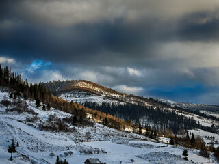 Mystical snowy Carpathian peaks under cloudy skies in the sunny weather