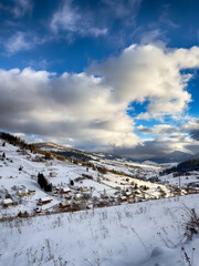Mystical snowy Carpathian peaks under cloudy skies in the sunny weather