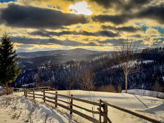 Mystical snowy Carpathian peaks under cloudy skies in the sunny weather