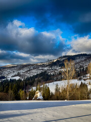 Mystical snowy Carpathian peaks under cloudy skies in the sunny weather