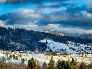 Mystical snowy Carpathian peaks under cloudy skies in the sunny weather