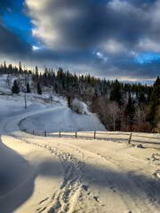 Mystical snowy Carpathian peaks under cloudy skies in the sunny weather