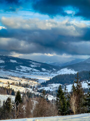Mystical snowy Carpathian peaks under cloudy skies in the sunny weather