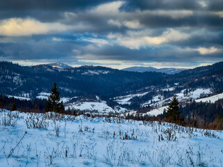 Mystical snowy Carpathian peaks under cloudy skies in the sunny weather