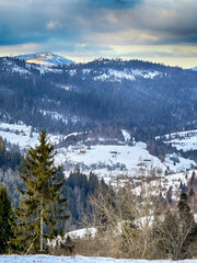 Mystical snowy Carpathian peaks under cloudy skies in the sunny weather