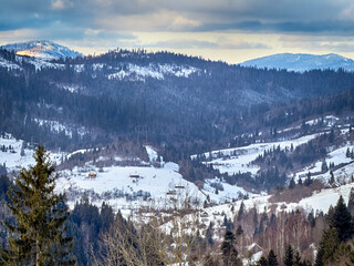 Mystical snowy Carpathian peaks under cloudy skies in the sunny weather