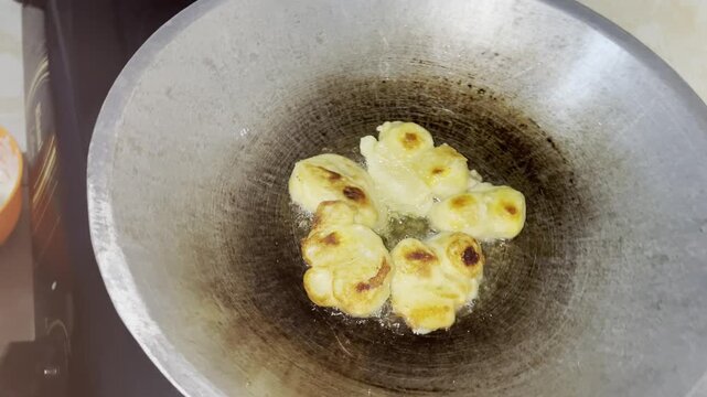 Frying cempedak fruit in batter, capturing sizzling process and authentic traditional cooking moment
