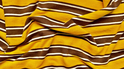 vibrant mustard yellow and chocolate brown striped knit fabric with slim white lines wrinkling softly in elegant folds perfect for autumn wallpaper or fashion banner background