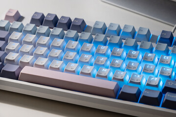 Fototapeta premium Mechanical keyboard with blue LED backlight on desk, modern technology workspace concept.