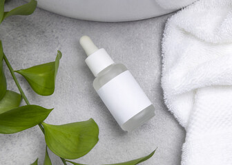 Spa Mockup, dropper bottle with label on grey stone near green leaves and towel, beauty treatments